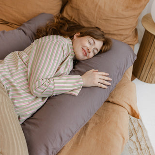 Pregnant woman relaxing with a MINICAMP U-shaped comfort pillow in cacao.